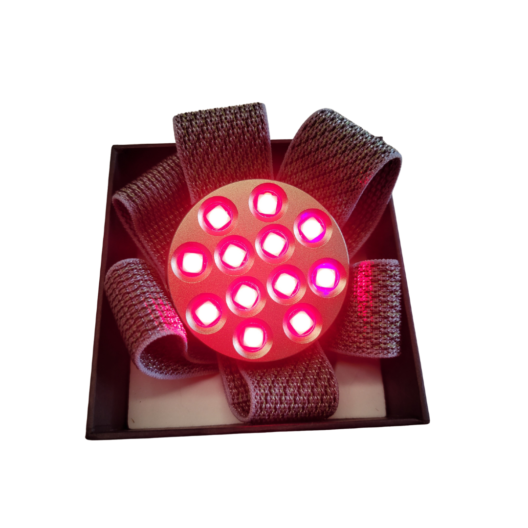 Compact red and near-infrared light therapy device with two positioning straps on a white background.